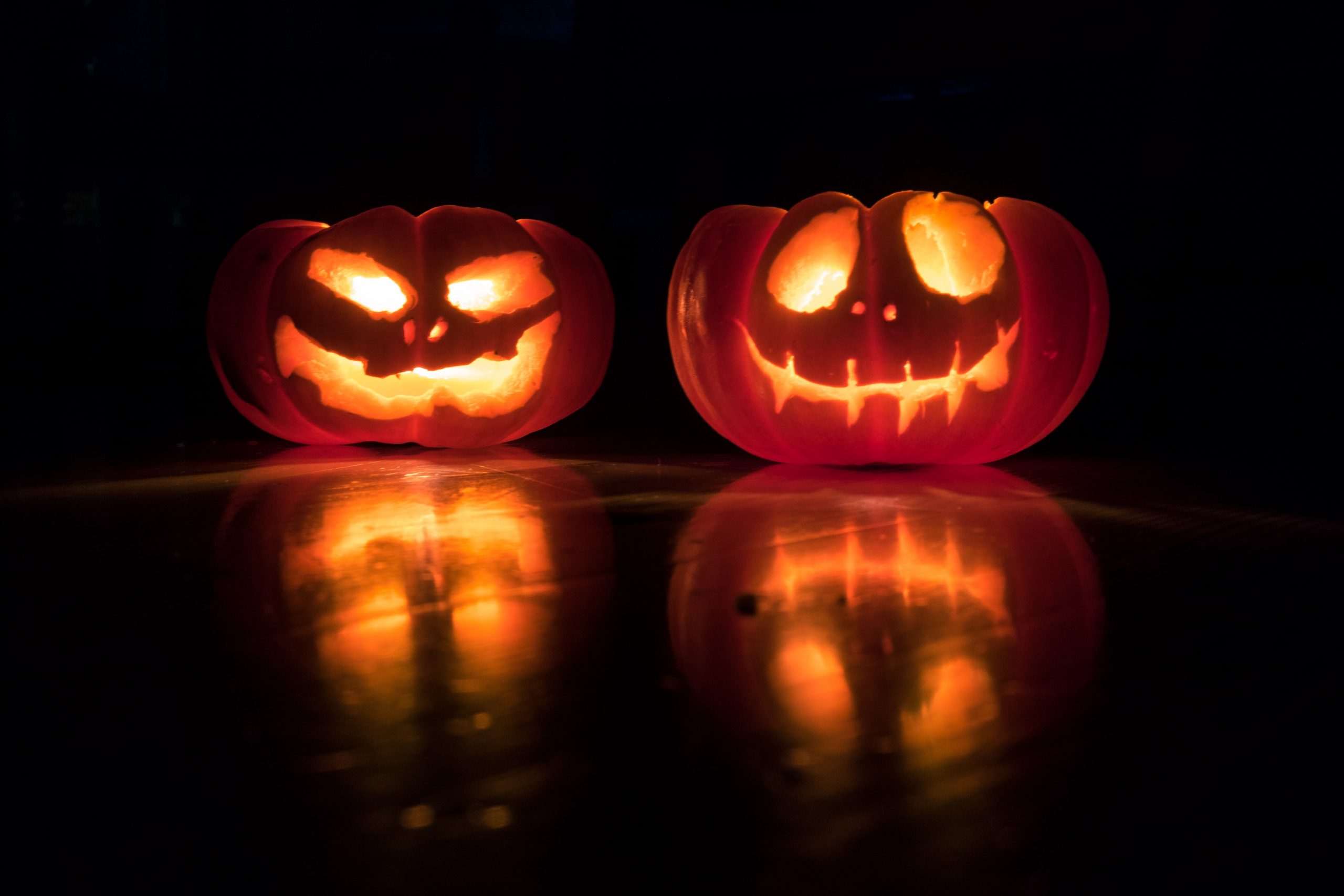 To Halloween-pyntede gresskar med lys inni seg. Foto.